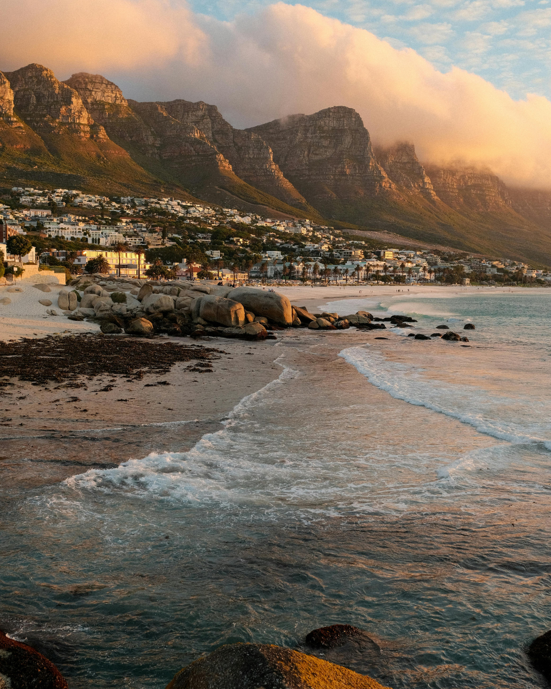 Camps Bay beach in Cape Town at golden hour with the Twelve Apostles mountains catching the sunset